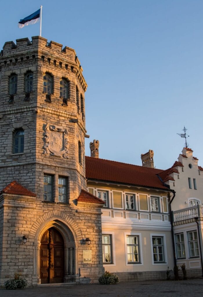 Ajalooline kivist hoone torni ja Eesti lipuga, valgustatud õhtupäikese poolt.