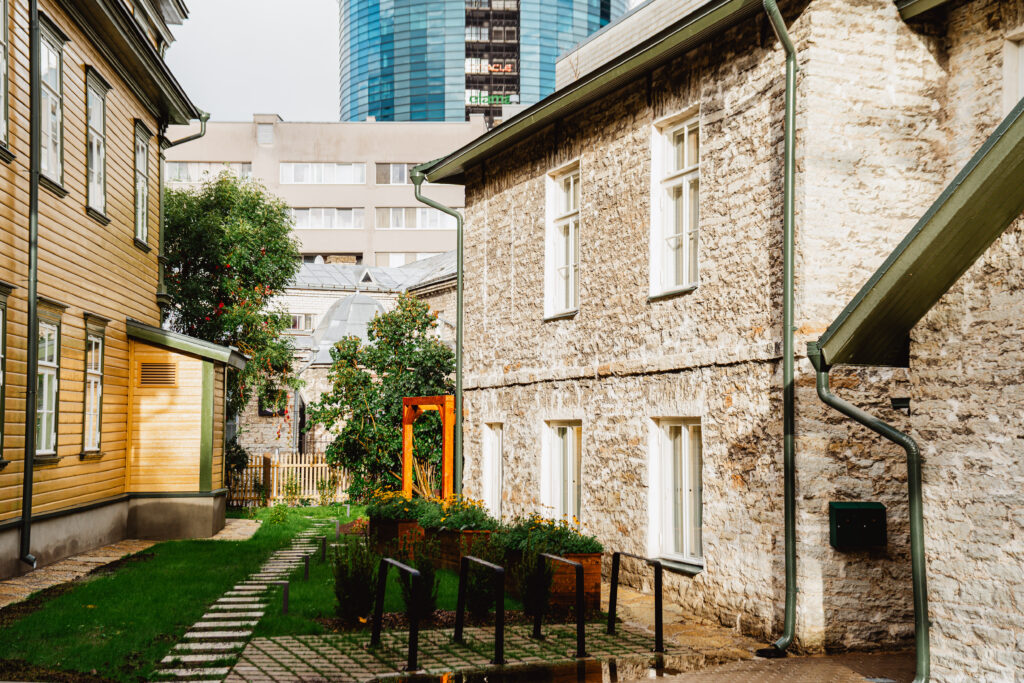 Renoveeritud paekivist ja puitfassaadiga hoonete sisehoov haljastuse ja kiviplaatidest kõnniteega – Tolira Ehitus, Tallinn.