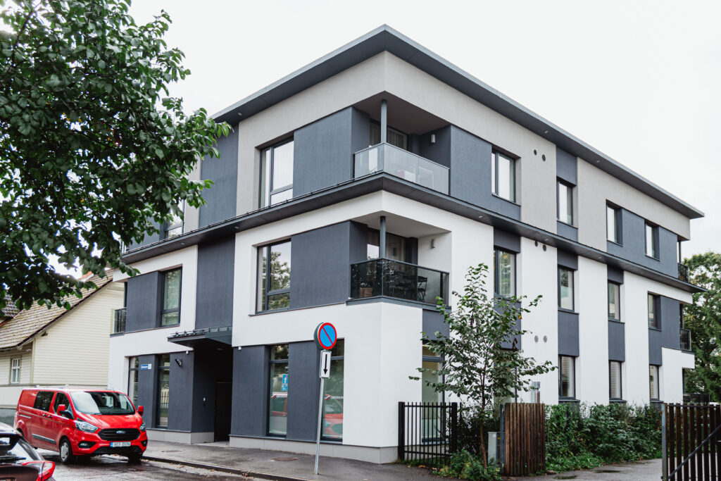 Kivimurru 14 tänavavaade, kus on nähtav modernne kolmekorruseline halli ja valge fassaadiga korterelamu ning selle ees parkiv punane kaubik.