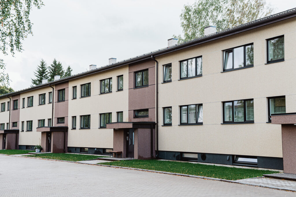 Kahekorruseline renoveeritud korterelamu beeži ja pruuni viimistlusega, hooldatud õueala ja sillutatud kõnniteega.